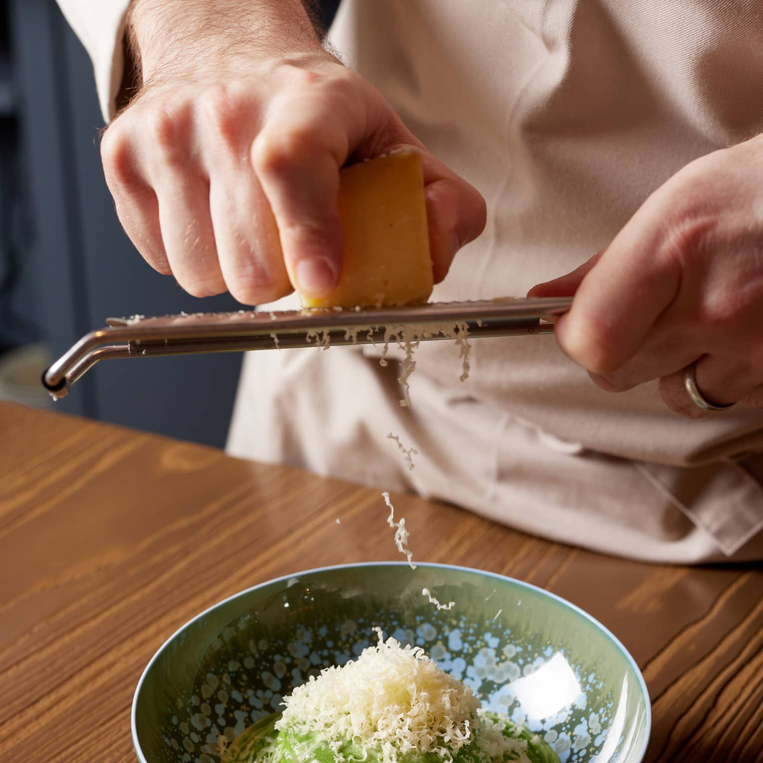 Chef grates Parmesan cheese over dish