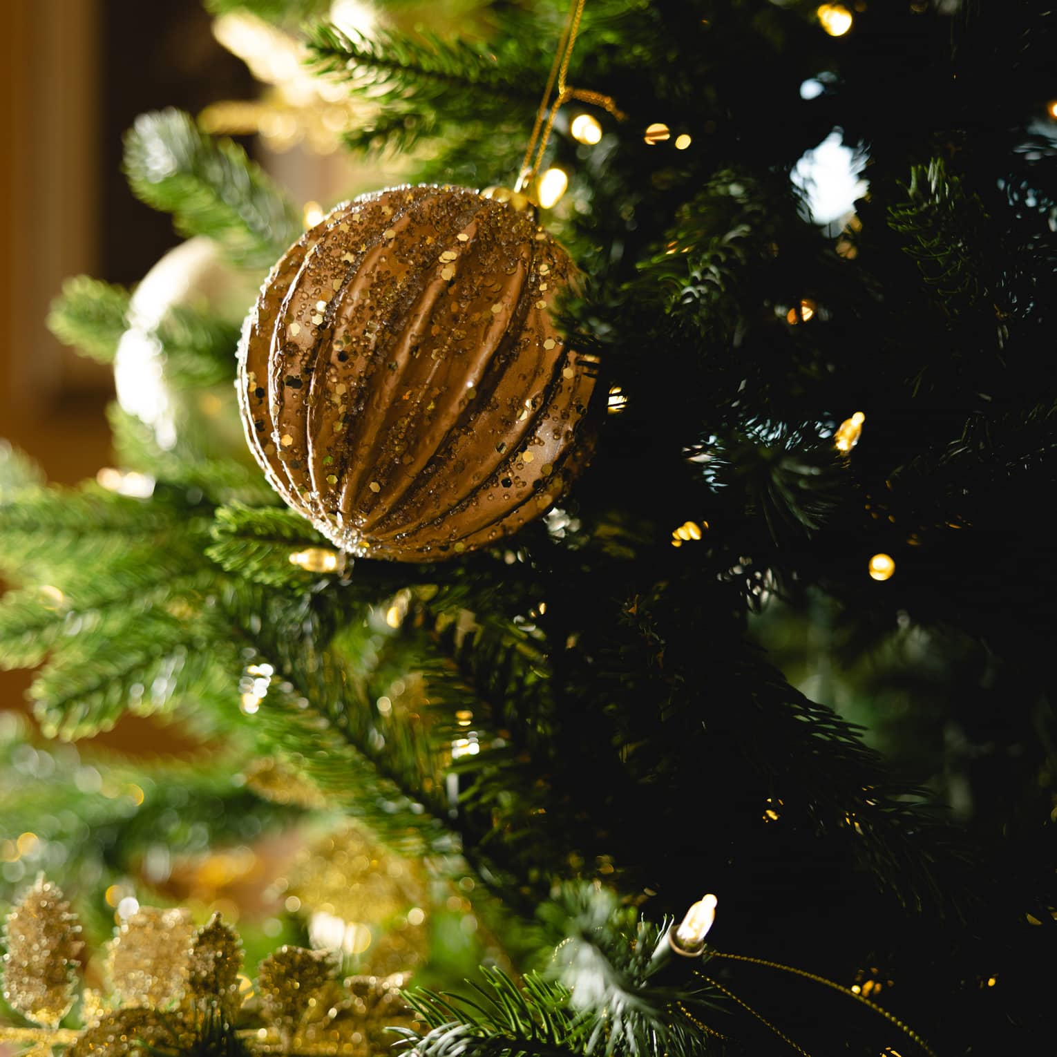 Gold ornament hangs on a Christmas tree