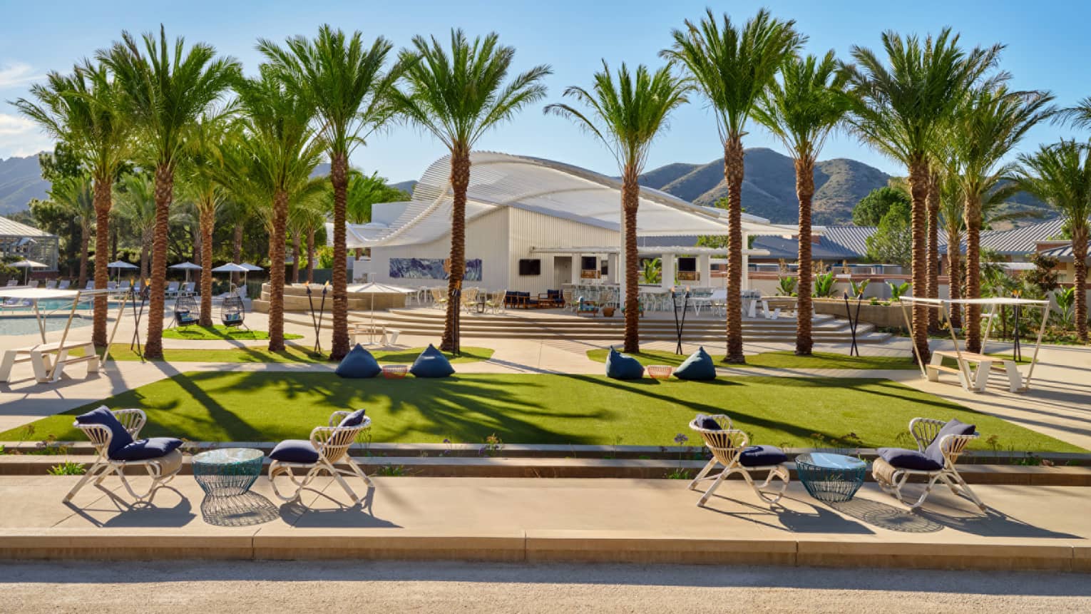 An outdoor sitting area with grass and palm trees.