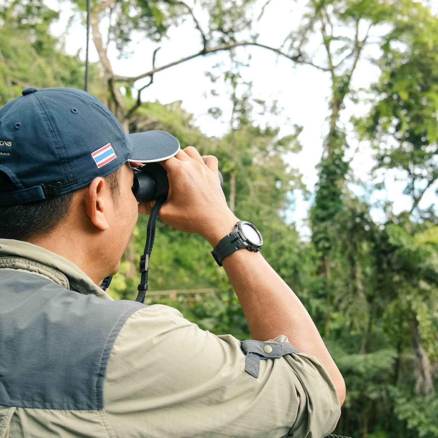 A man looks for birds through binoculars in jungle