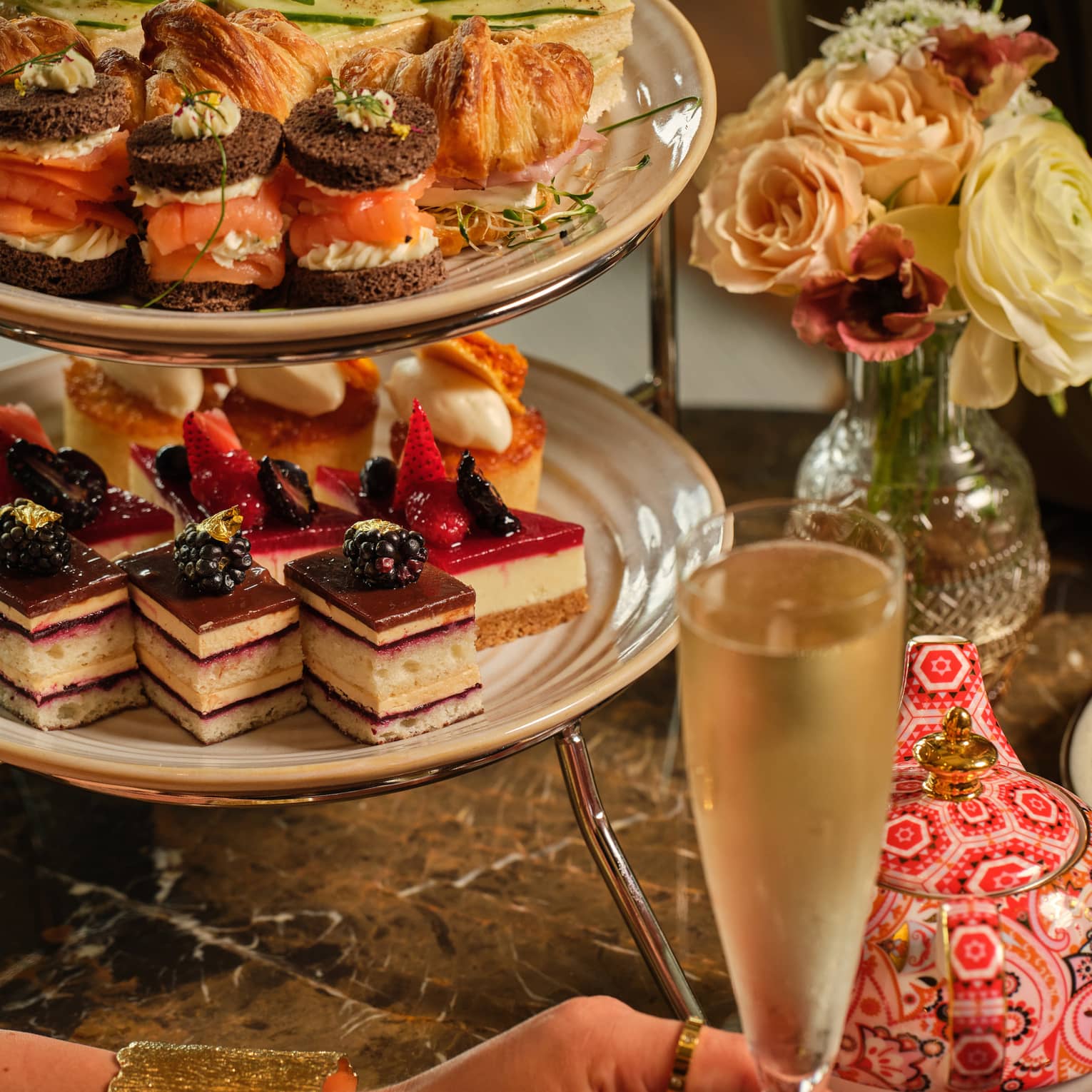 A three-tiered display of sweets beside a vase of flowers