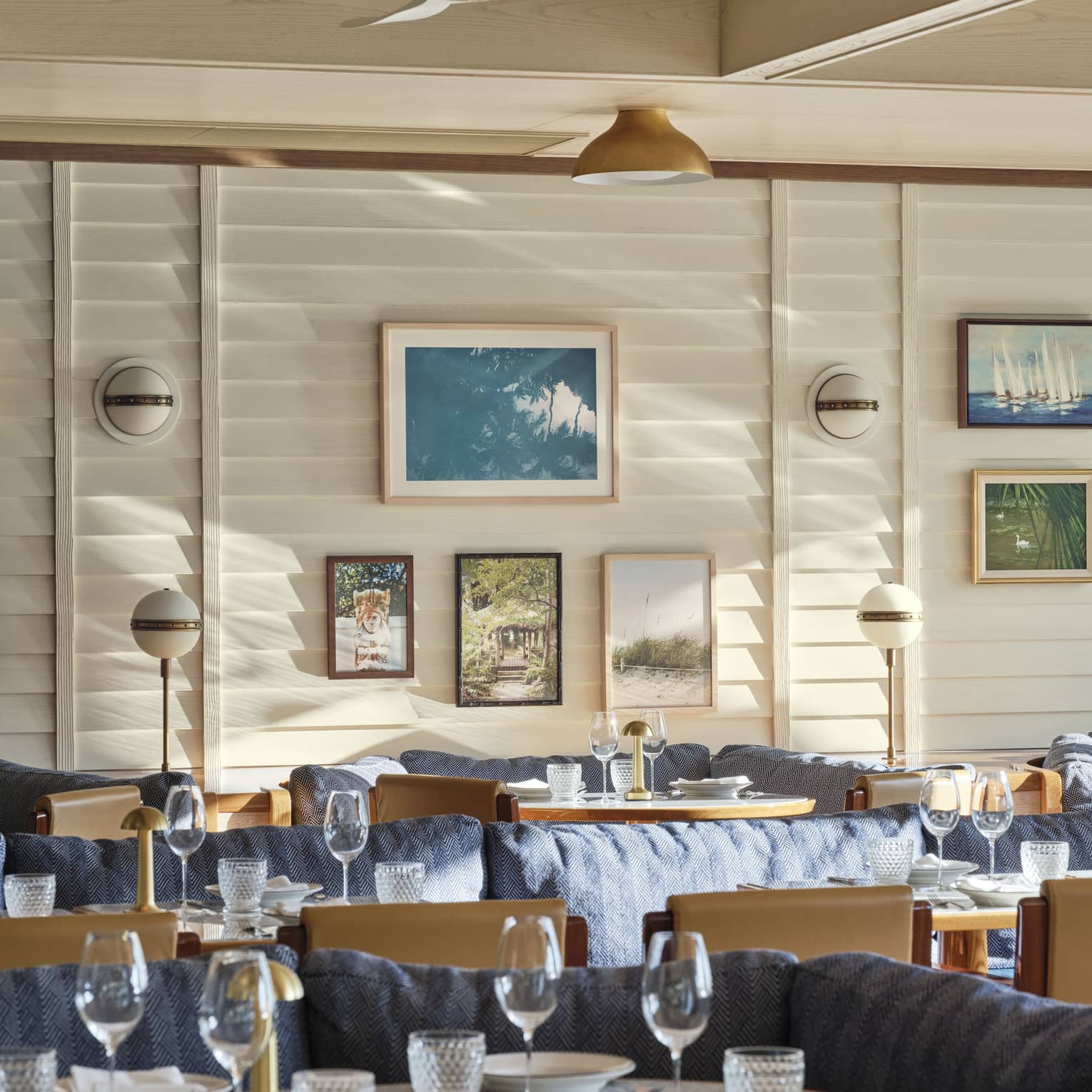 The interior of a restaurant with large booths with blue cushions and art on a wall.