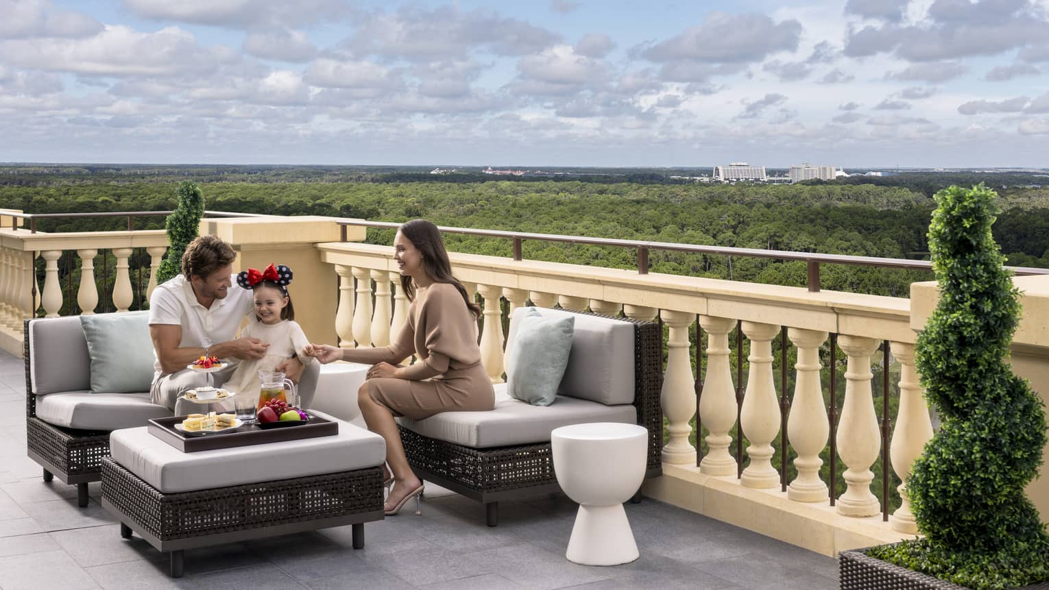 Man, woman and young girl sit on outdoor terrace