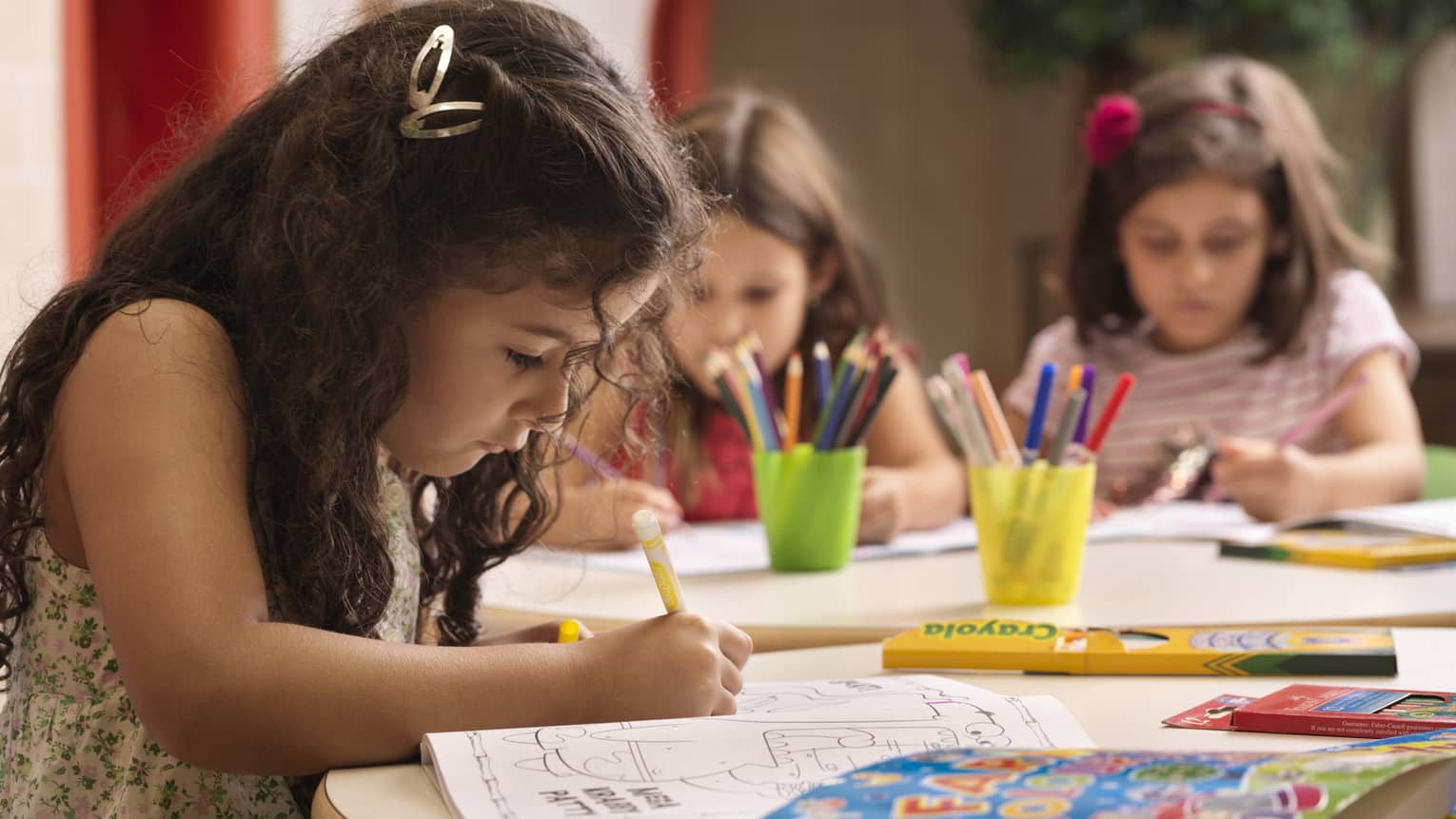 A group of young girls using markers on colouring books.