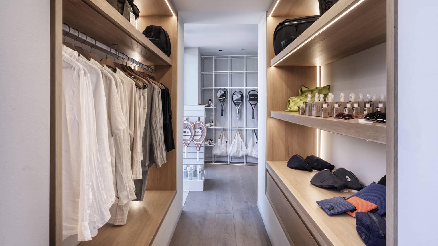 A room with shelves and clothes on hangars.