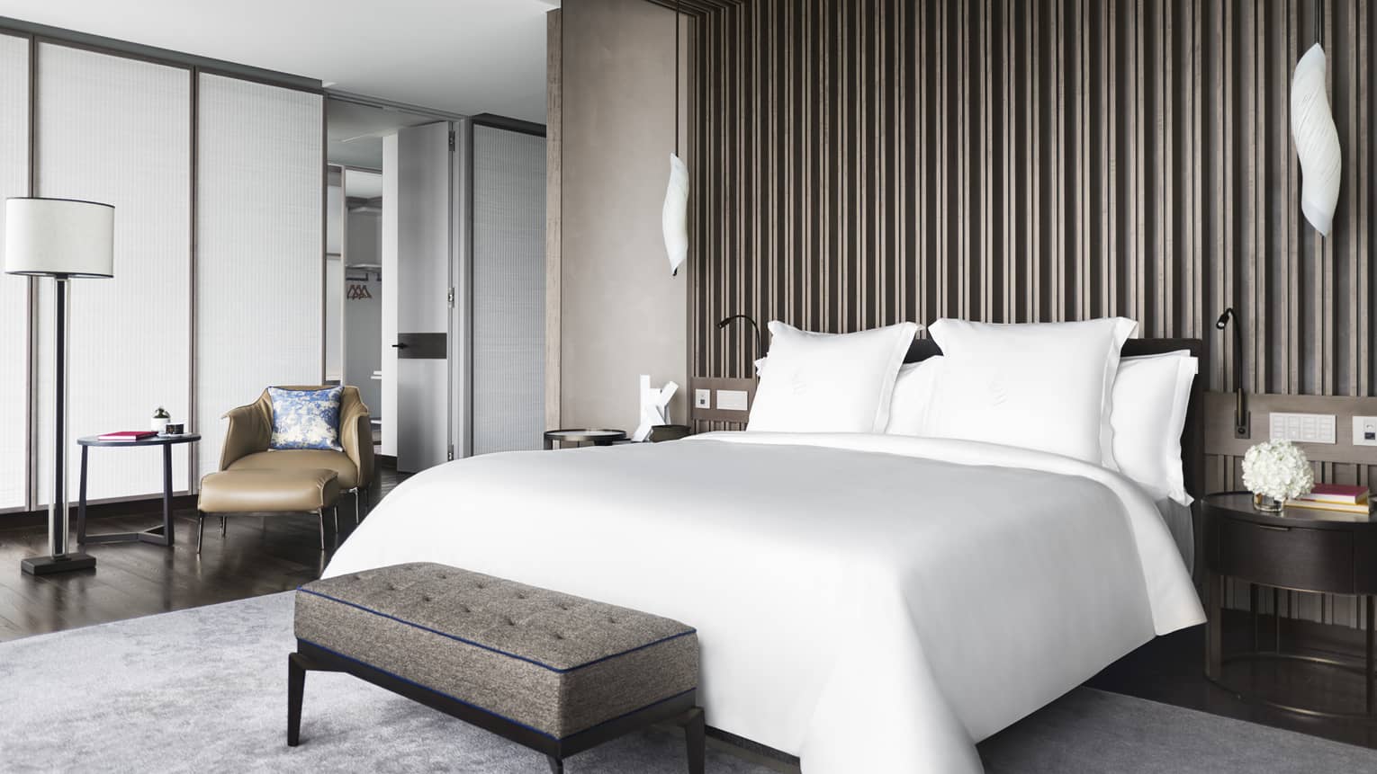 Hotel suite bedroom with white king bed and wooden accent wall/ceiling