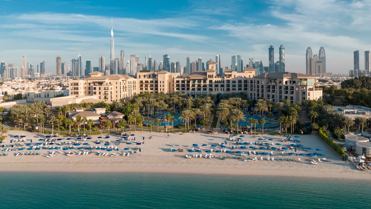 An aerial view of Dubai Jumeirah Beach of the ocean, with the city skyline behind.