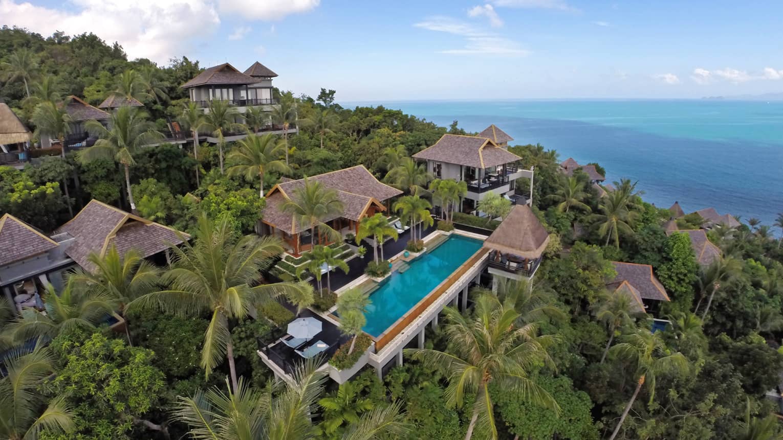 Aerial view of owner's residence villa complex around blue swimming pool, patio on tropical mountain