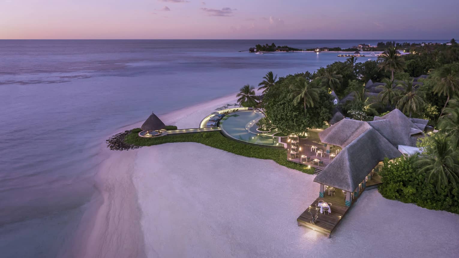 Aerial view of beach and Resort's illuminated deck with pool