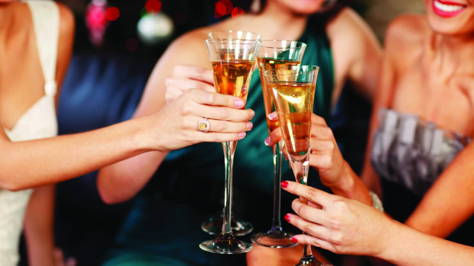 Close-up of women in evening gowns toasting with glasses of Champagne