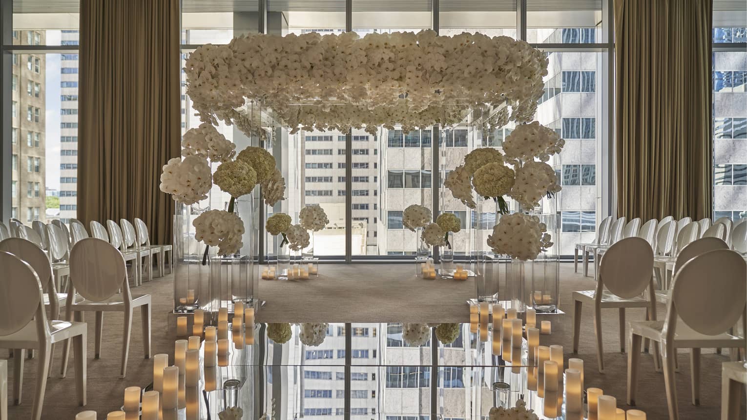 Wedding ceremony set up in event room, mirror aisle lined with candles leading to flower covered altar