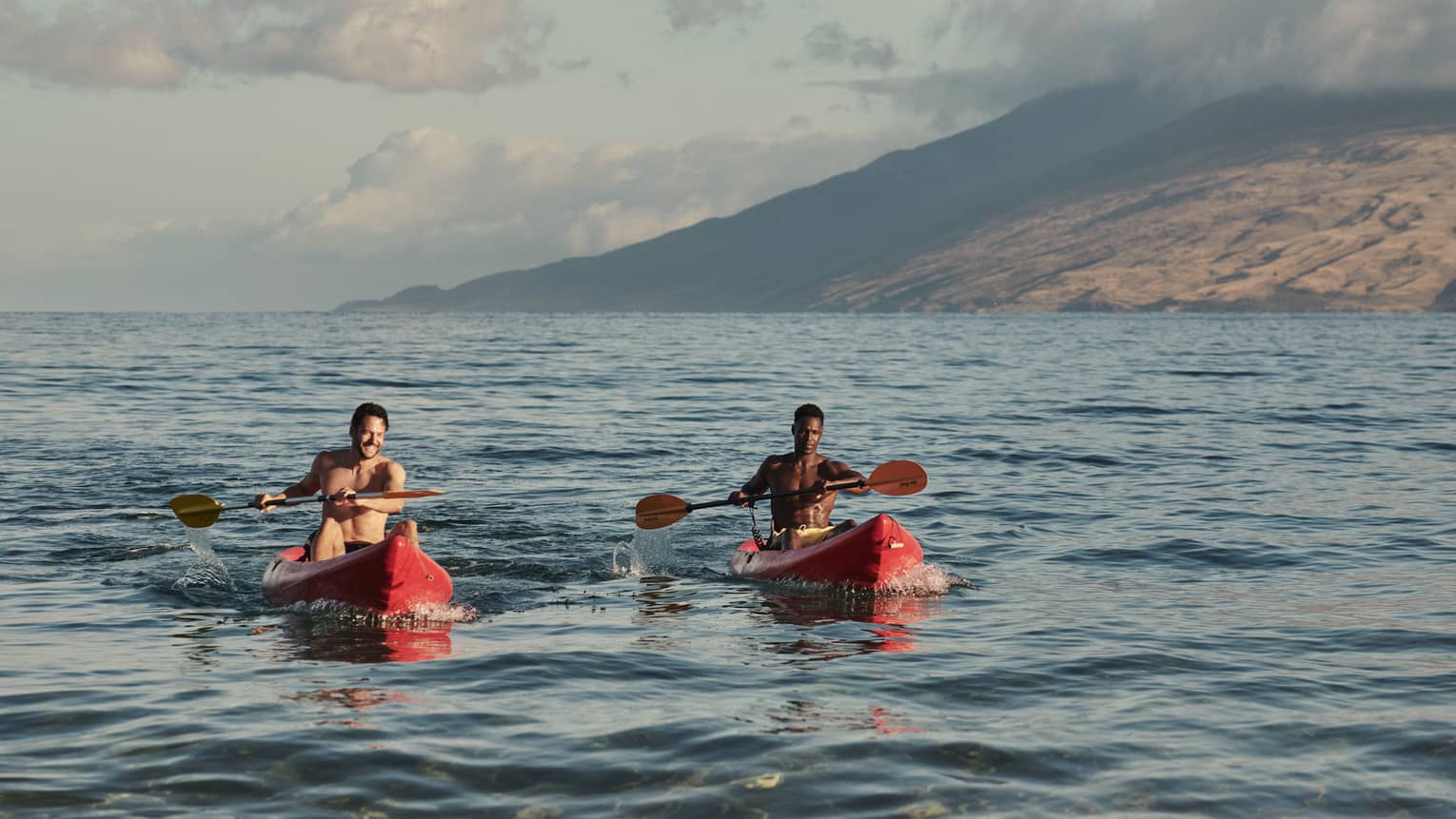 Two men in red kayaks in the ocean in Maui
