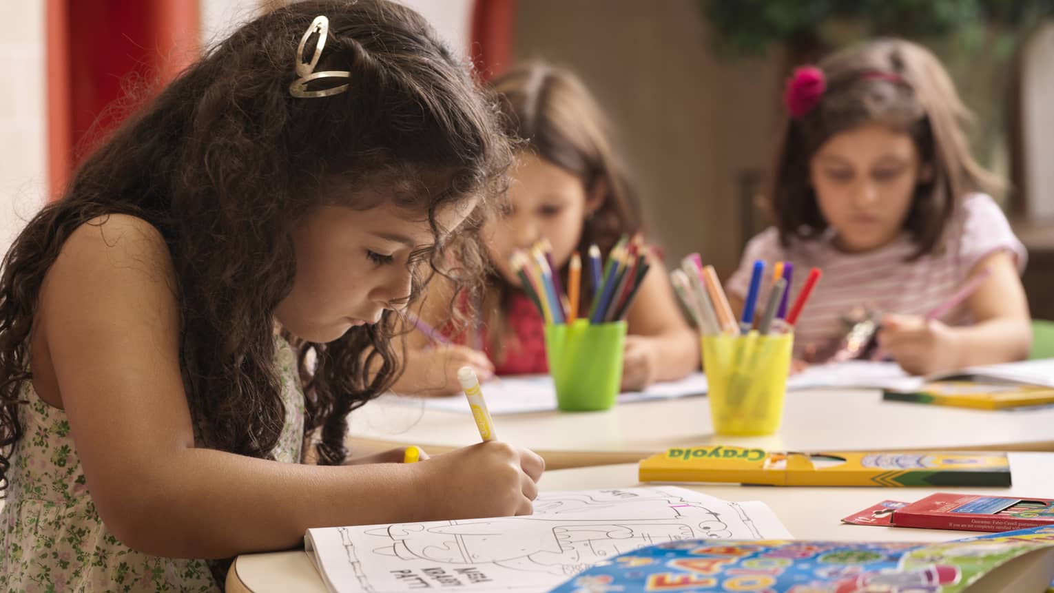 A group of young girls using markers on colouring books.