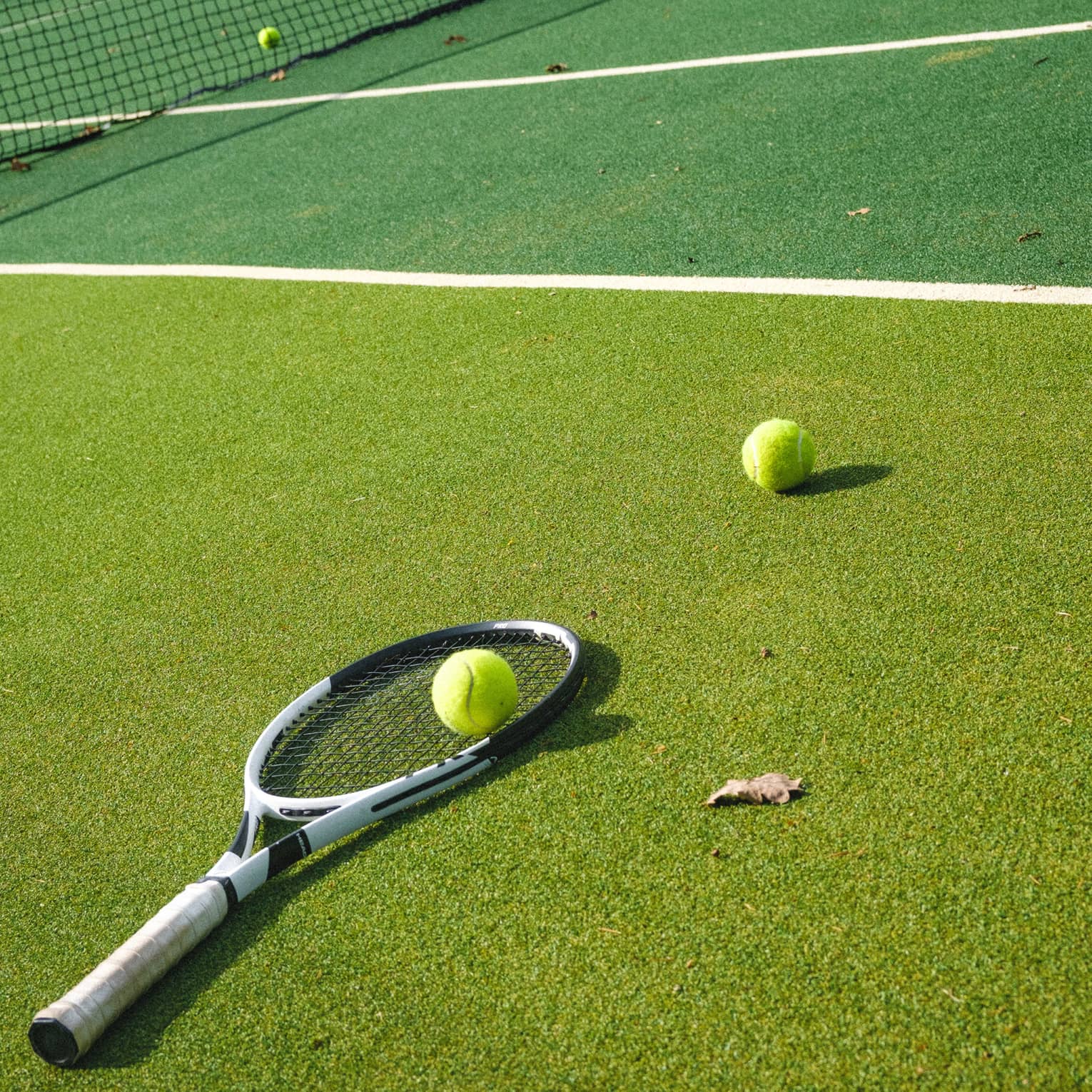 Tennis racquet and two tennis balls on two-tone tennis court