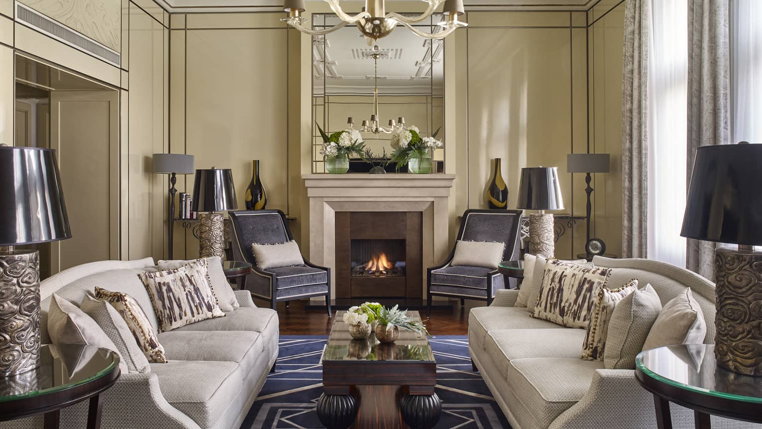 Grand sitting room in Royal Suite with fireplace, two couches, rug, lamps, drapes