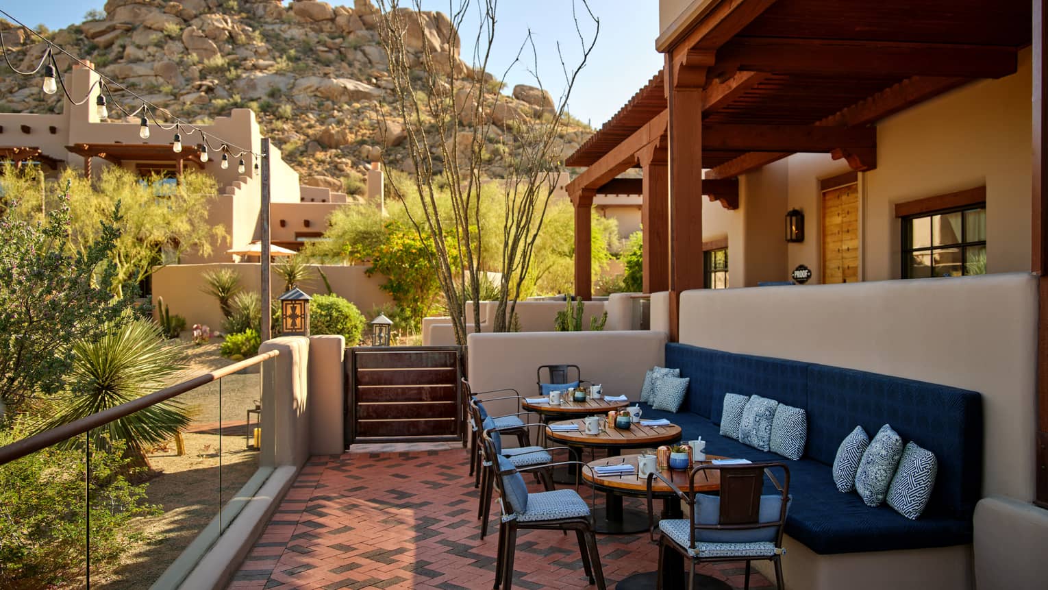 Outdoor terrace with booth seating and chairs and a view of the mountains.