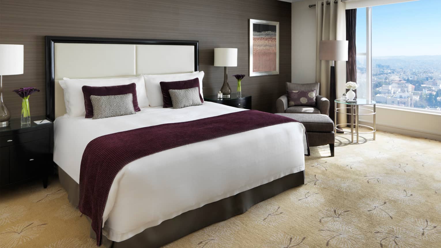 Premium room bed with burgundy blanket, wood-grain wall, plush carpet, window overlooking Abdoun area