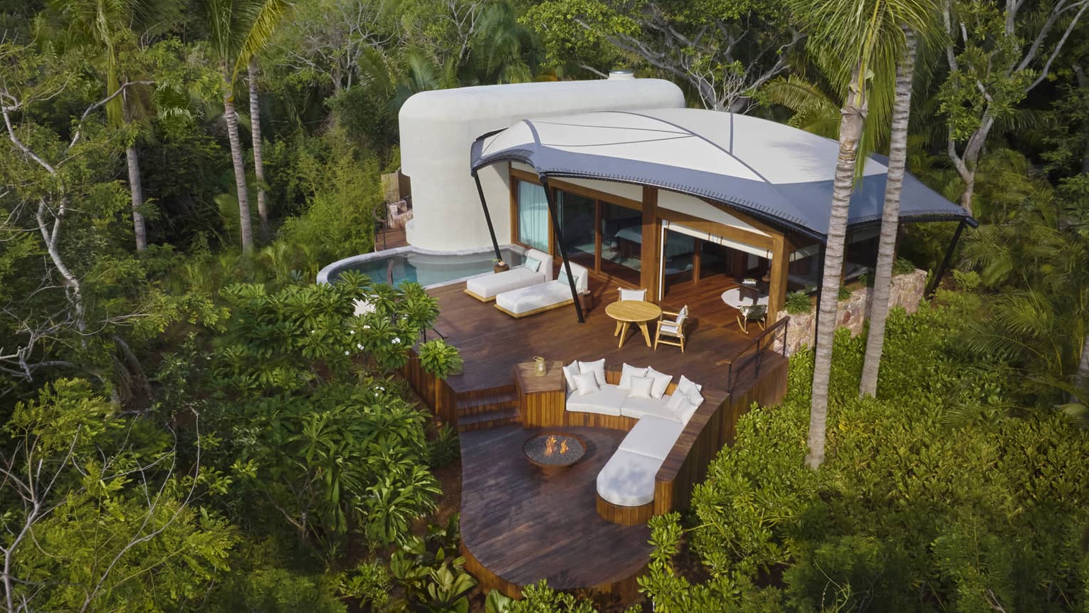 Aerial view of a luxury tent with pool and firepit in the jungle