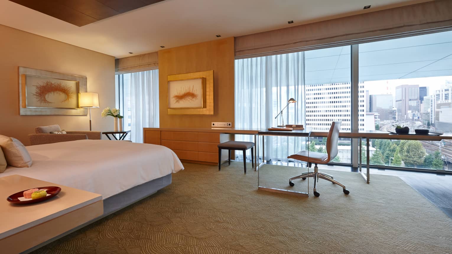 Premier Room bed, large desk in front of windows, armchair under framed art