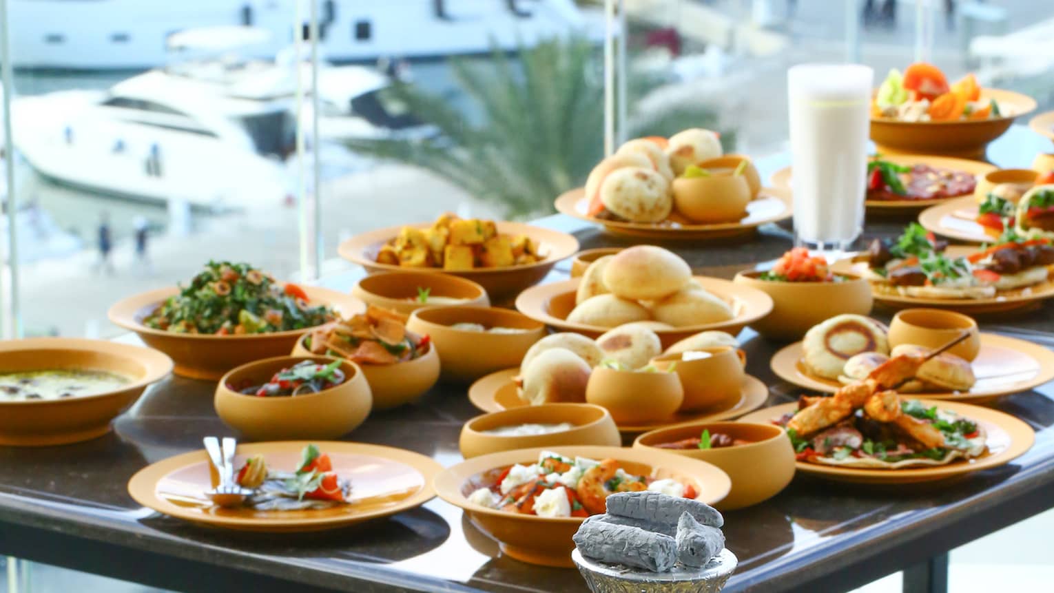 Shisha beside table with small appetizer dishes, window with view over yachts