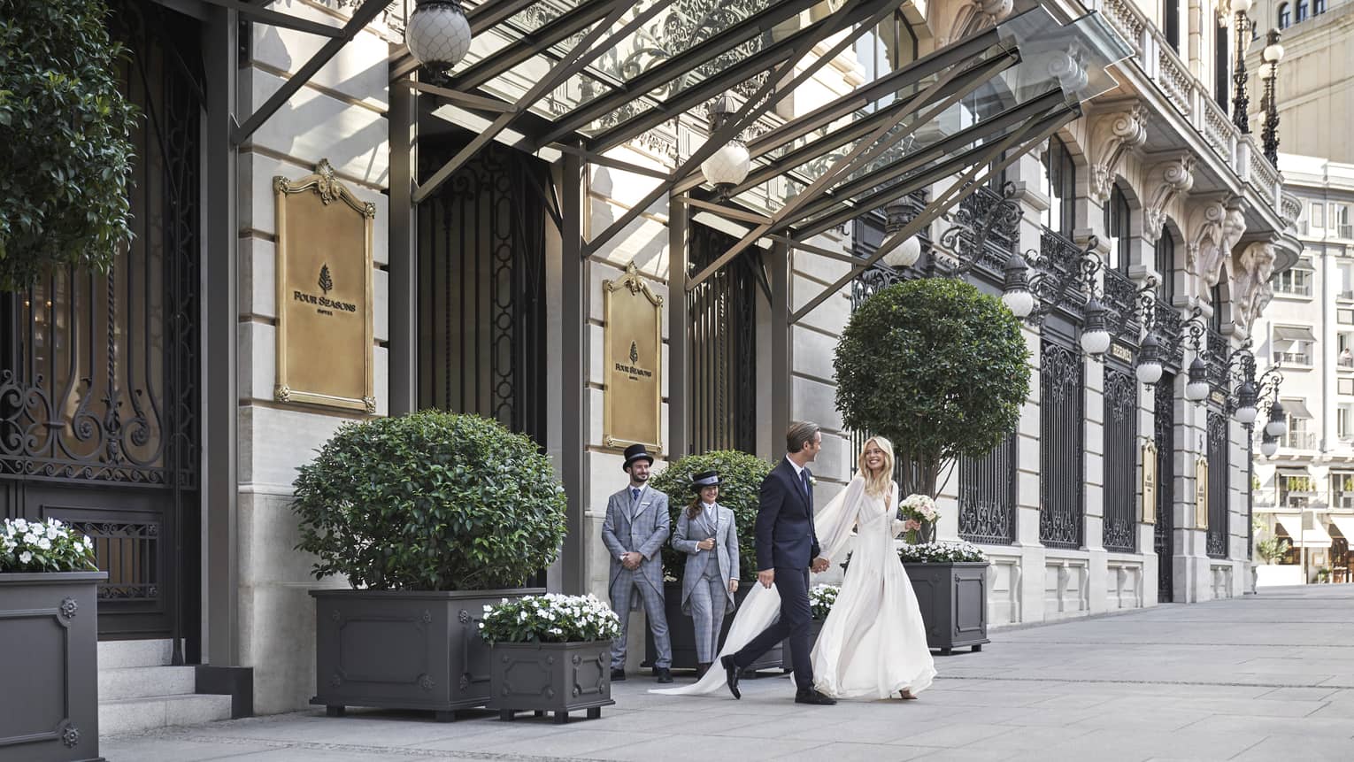 A wedding couple walking out the front door of the hotel.