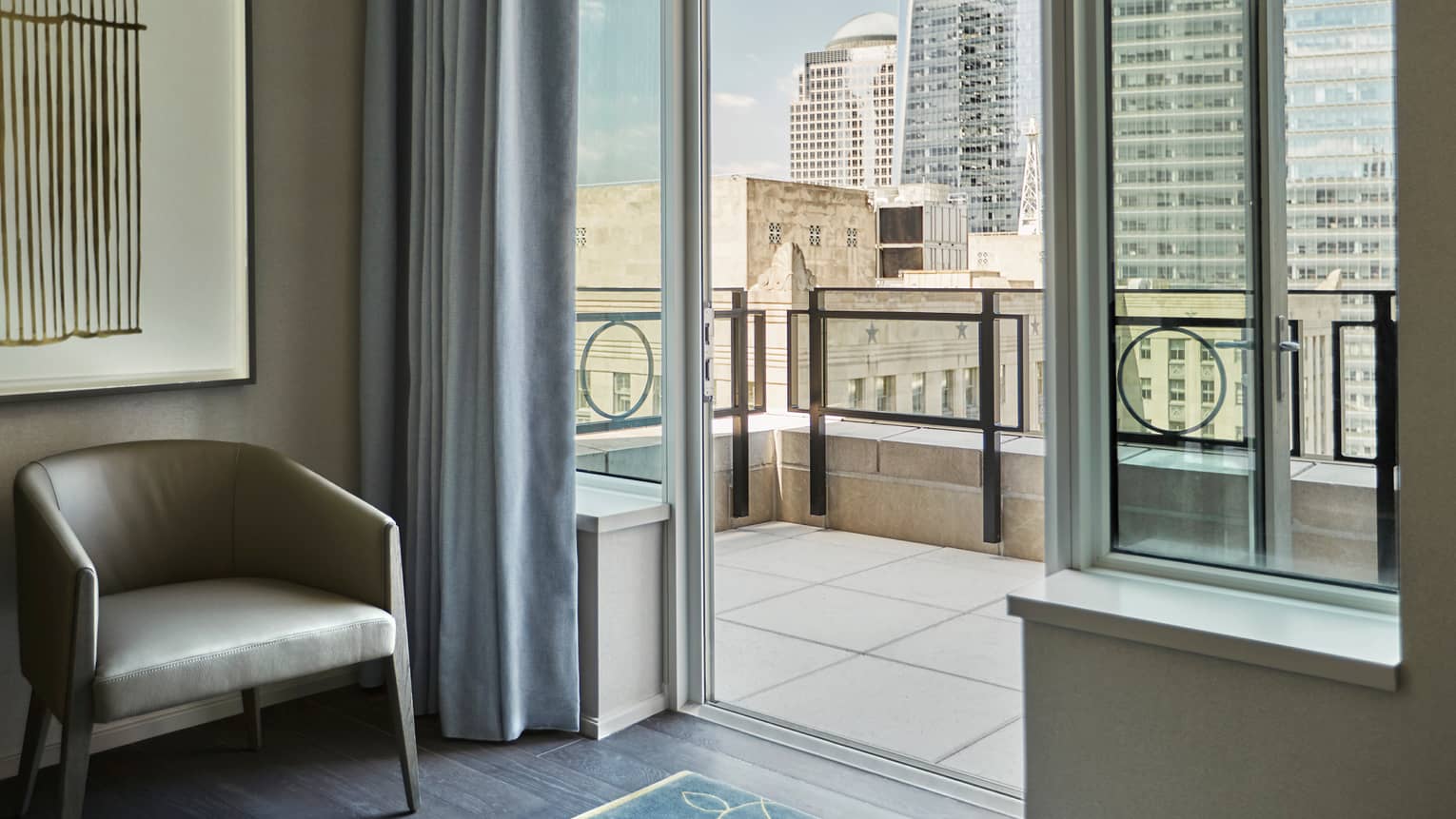 Tribeca Suite leather mid-century style chair by open door to tile balcony overlooking downtown New York