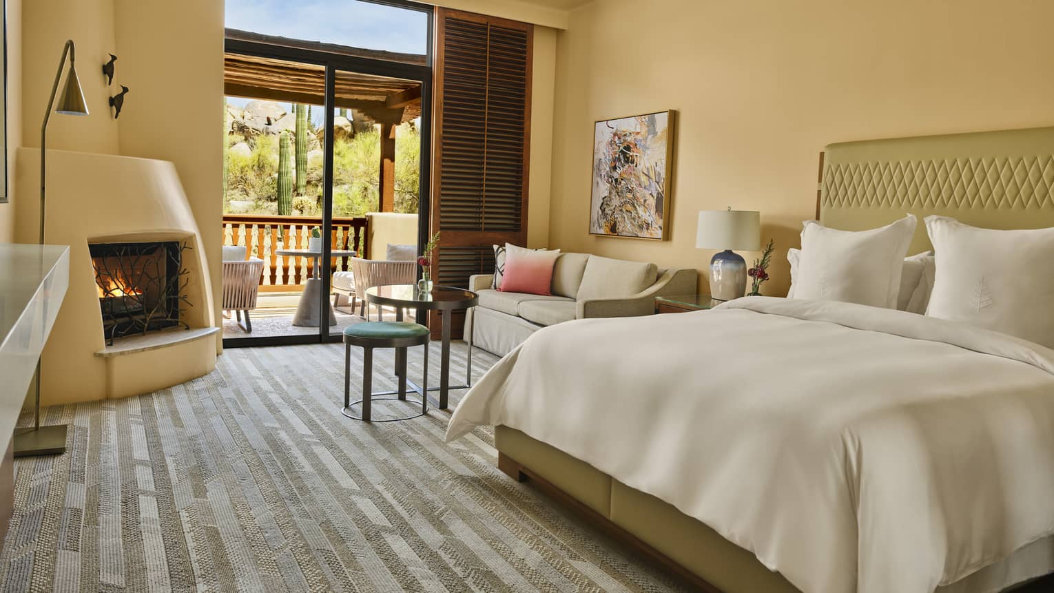 Resort guest room featuring king bed, seating area with small sofa, a kiva fireplace and a walk-out terrace