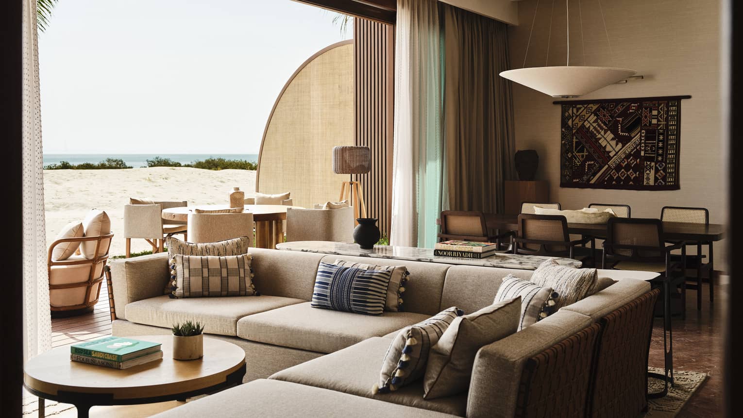 Resort suite featuring a sectional sofa, dining table and a wall opening to sea-view terrace
