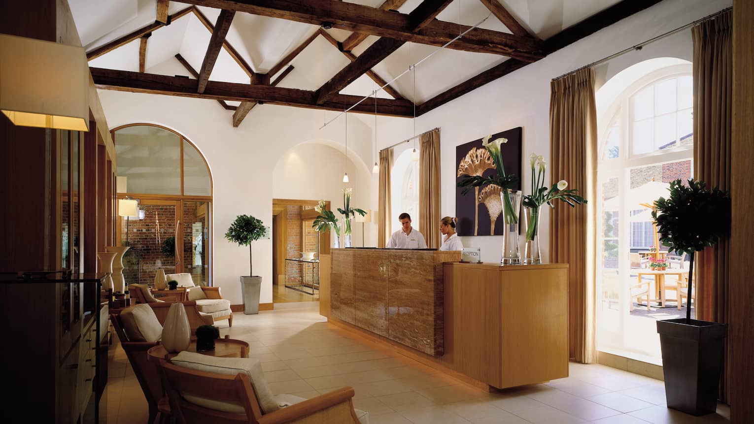 Staff at Spa reception desk under wood beam ceiling, tall bright windows