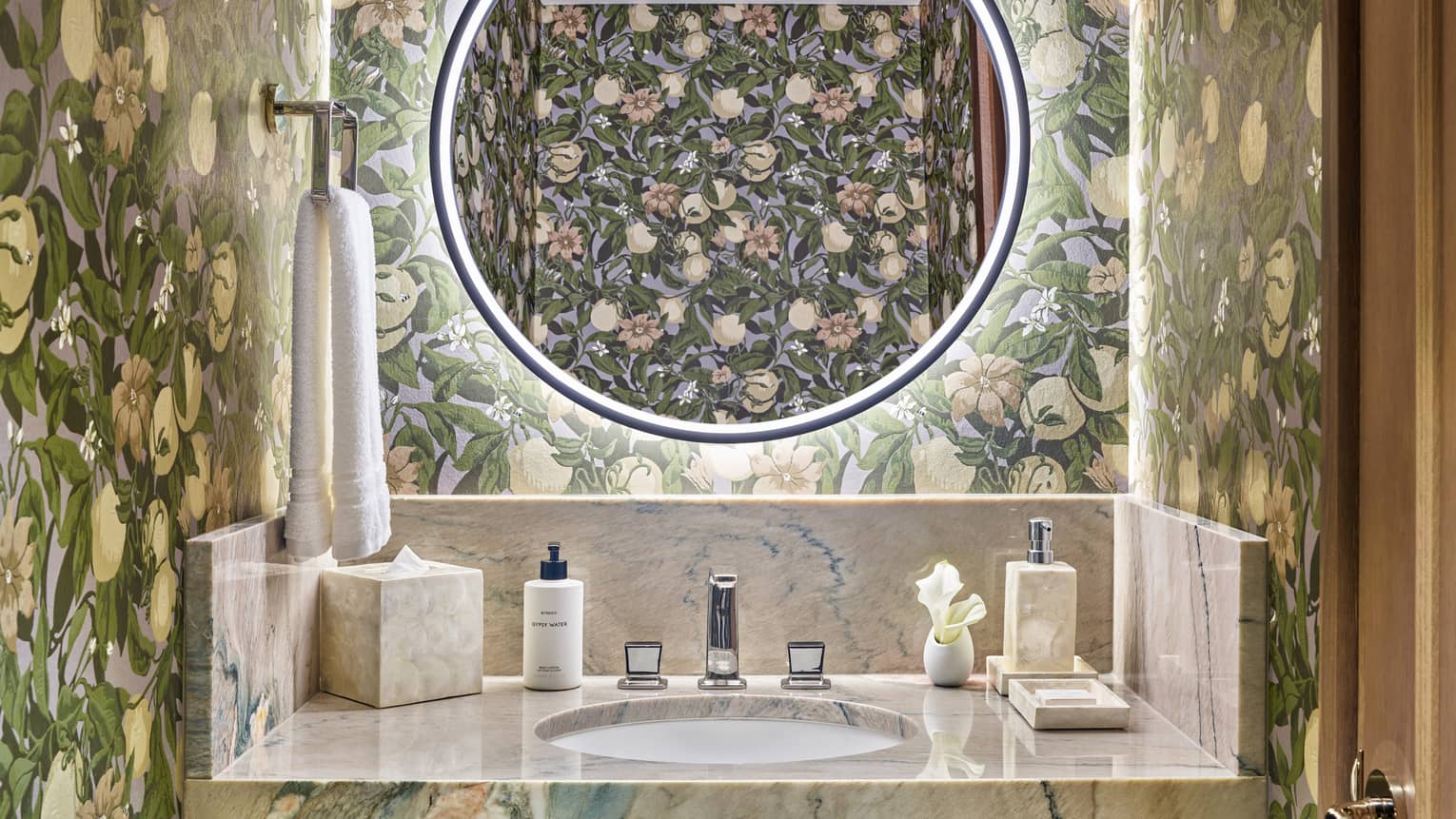 Bathroom with floral wall paper, illuminated round mirror, marble vanity
