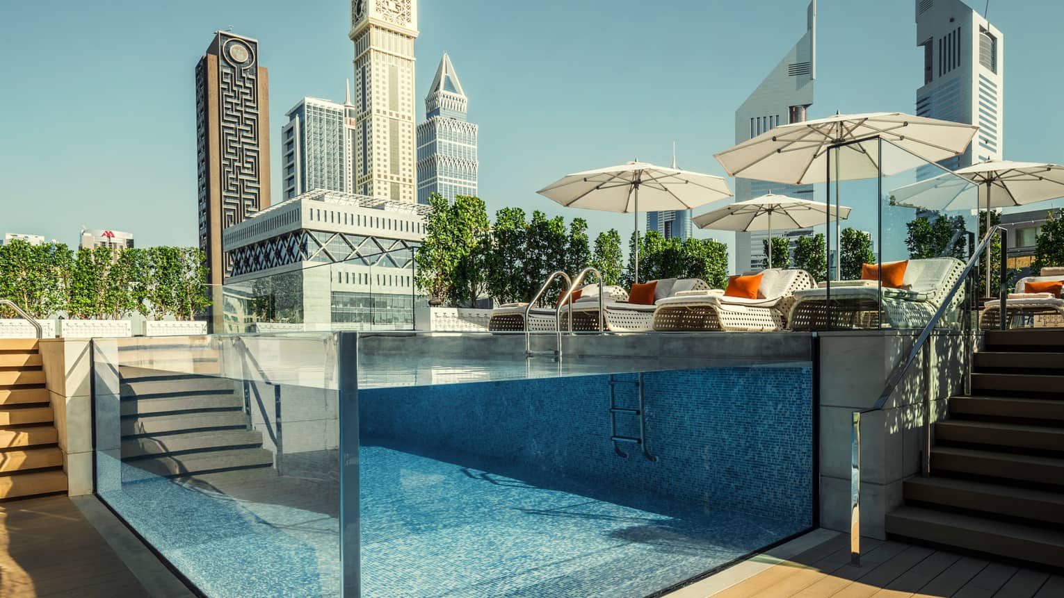 Raised glass plunge pool by stairs on patio deck, lounge chairs, umbrella