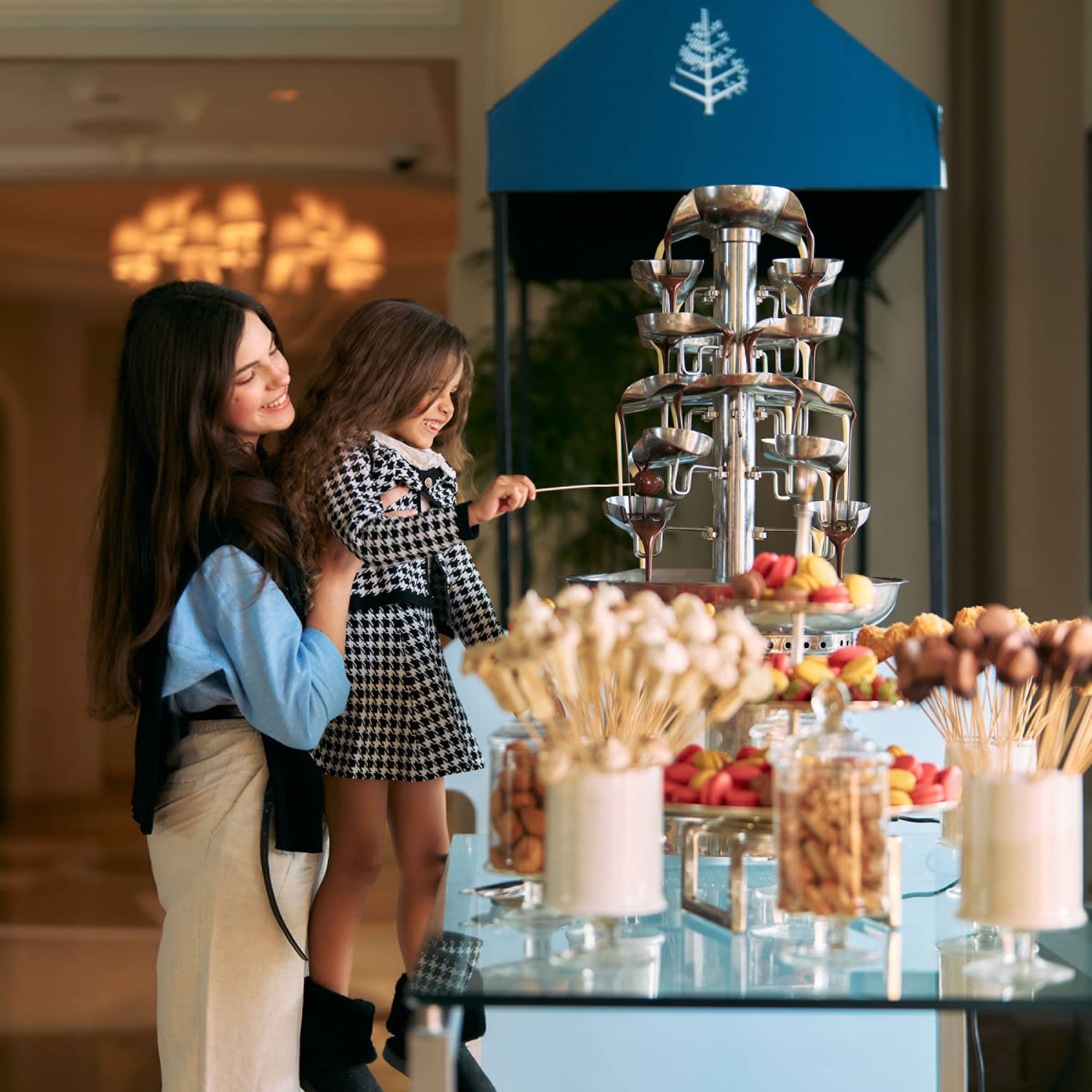 Adult lifts a small child up to grab a pastry from a buffet display