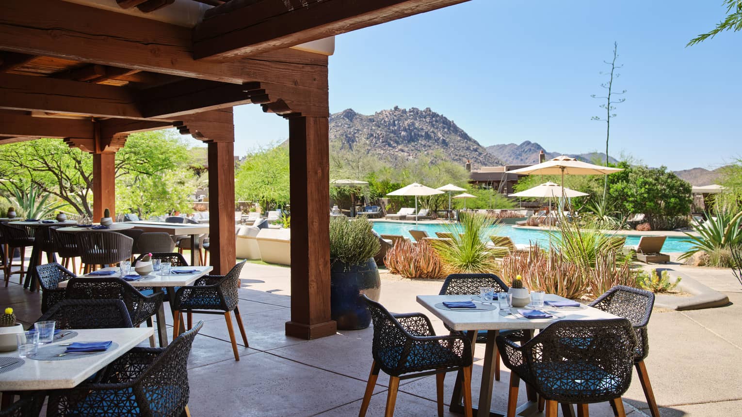 Outdoor patio with table and chairs, view of the pool, and mountains in the background.