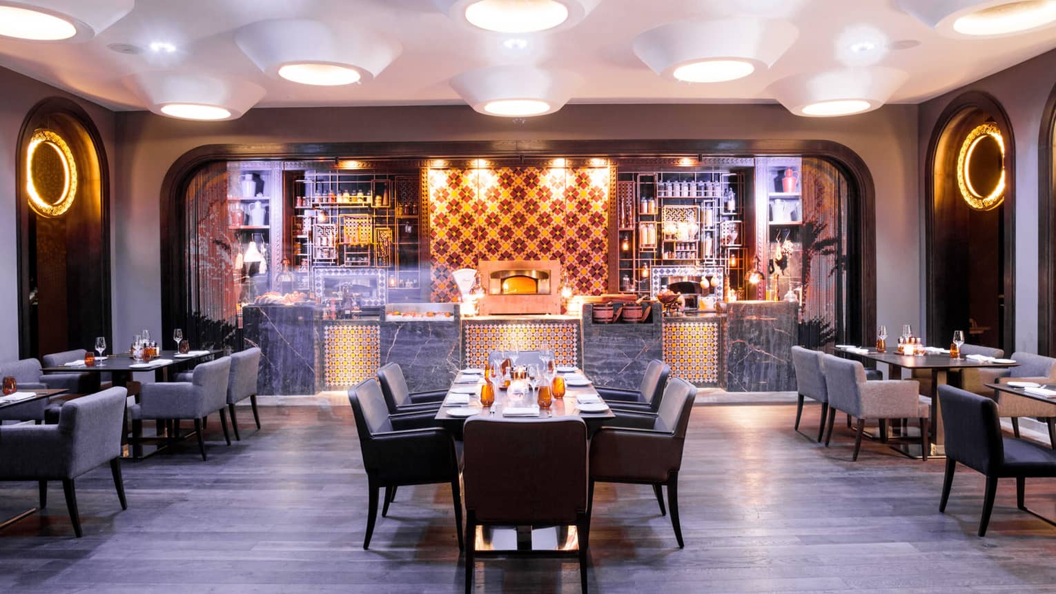 Quattro dining room, tables and chairs in front of illuminated bar 