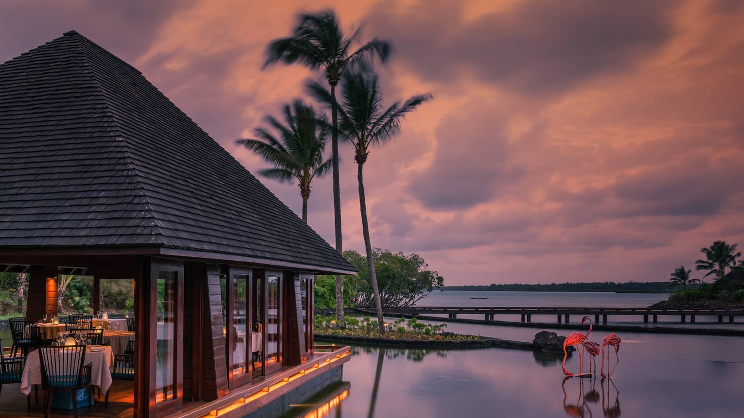 Beau Champ restaurant pavilion at sunset, two pink flamingo sculptures in water