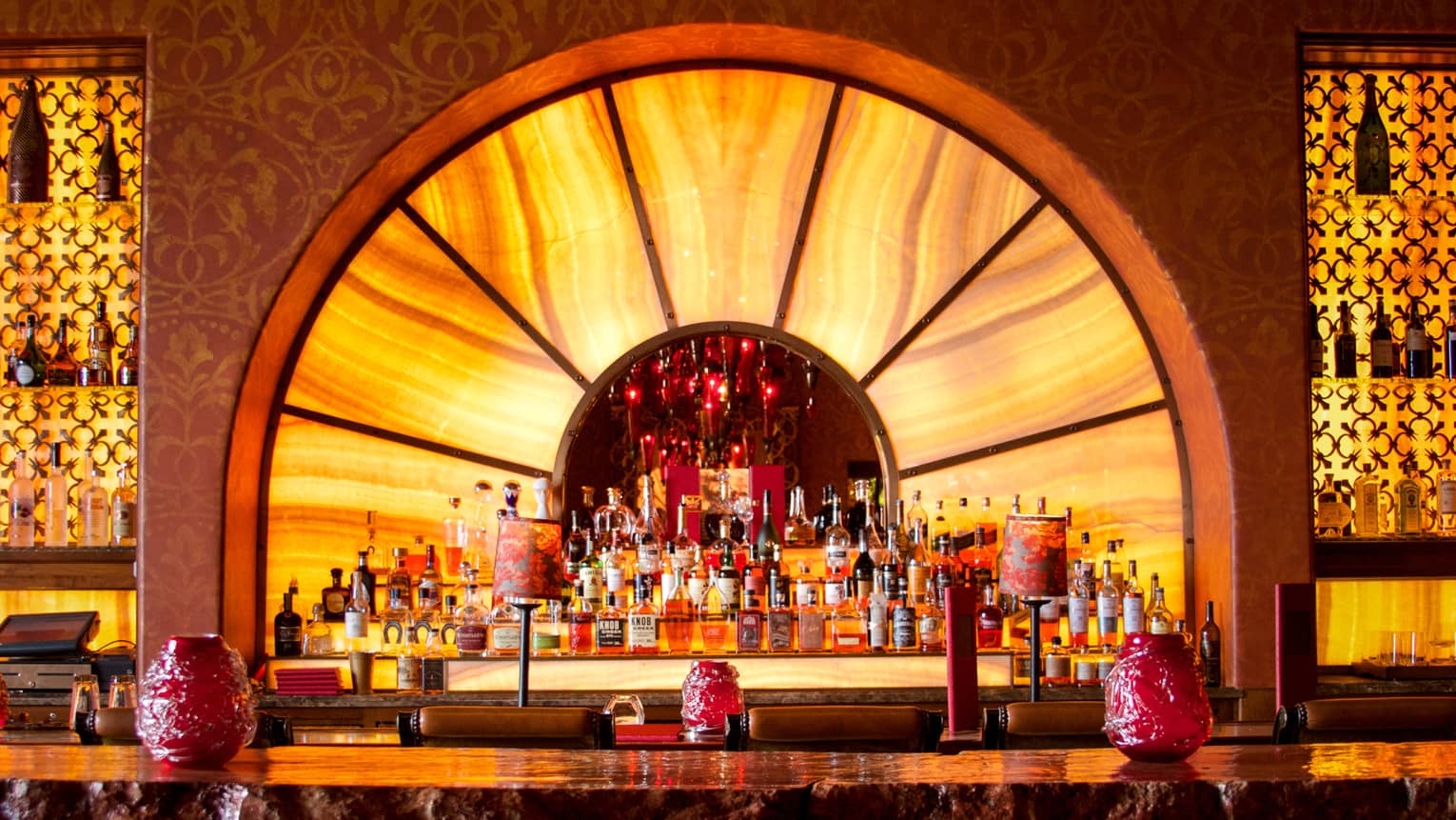 Ty Lounge yellow arch on wall behind bar, three-tiered liquor display, red glass lights lanterns