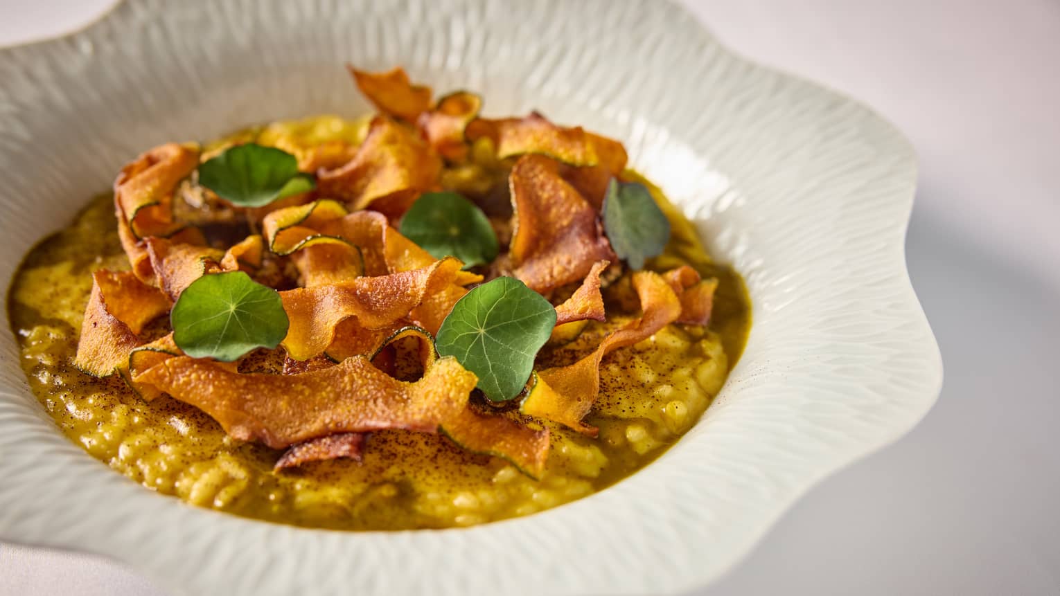 A pumpkin risotto dish served in a white bowl.