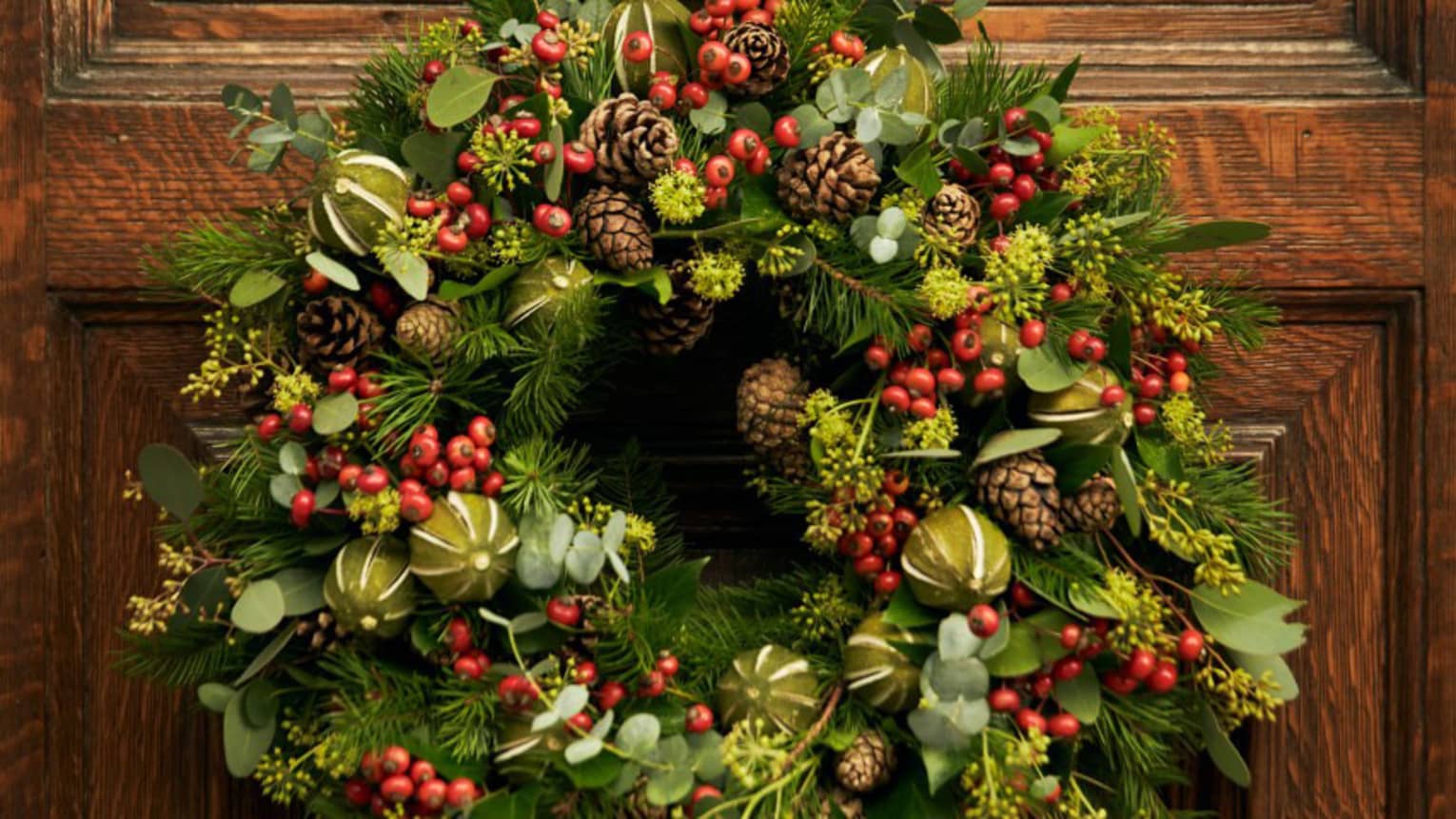 A wreath with red berries hanging on a wood door.