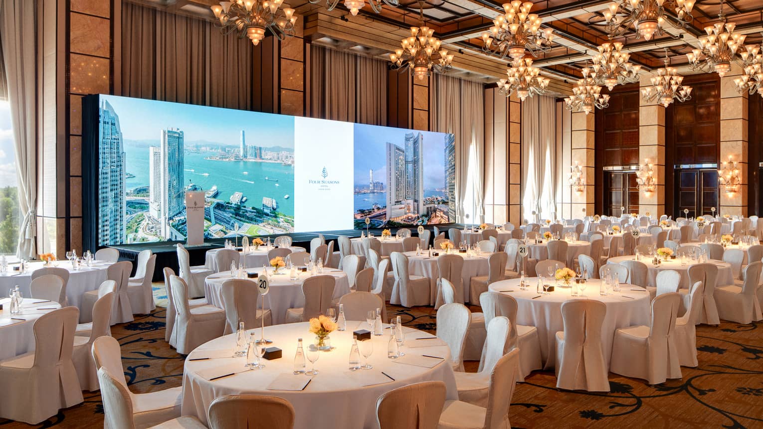 Large hotel ballroom with banquet seating an wide screen in the front of the room