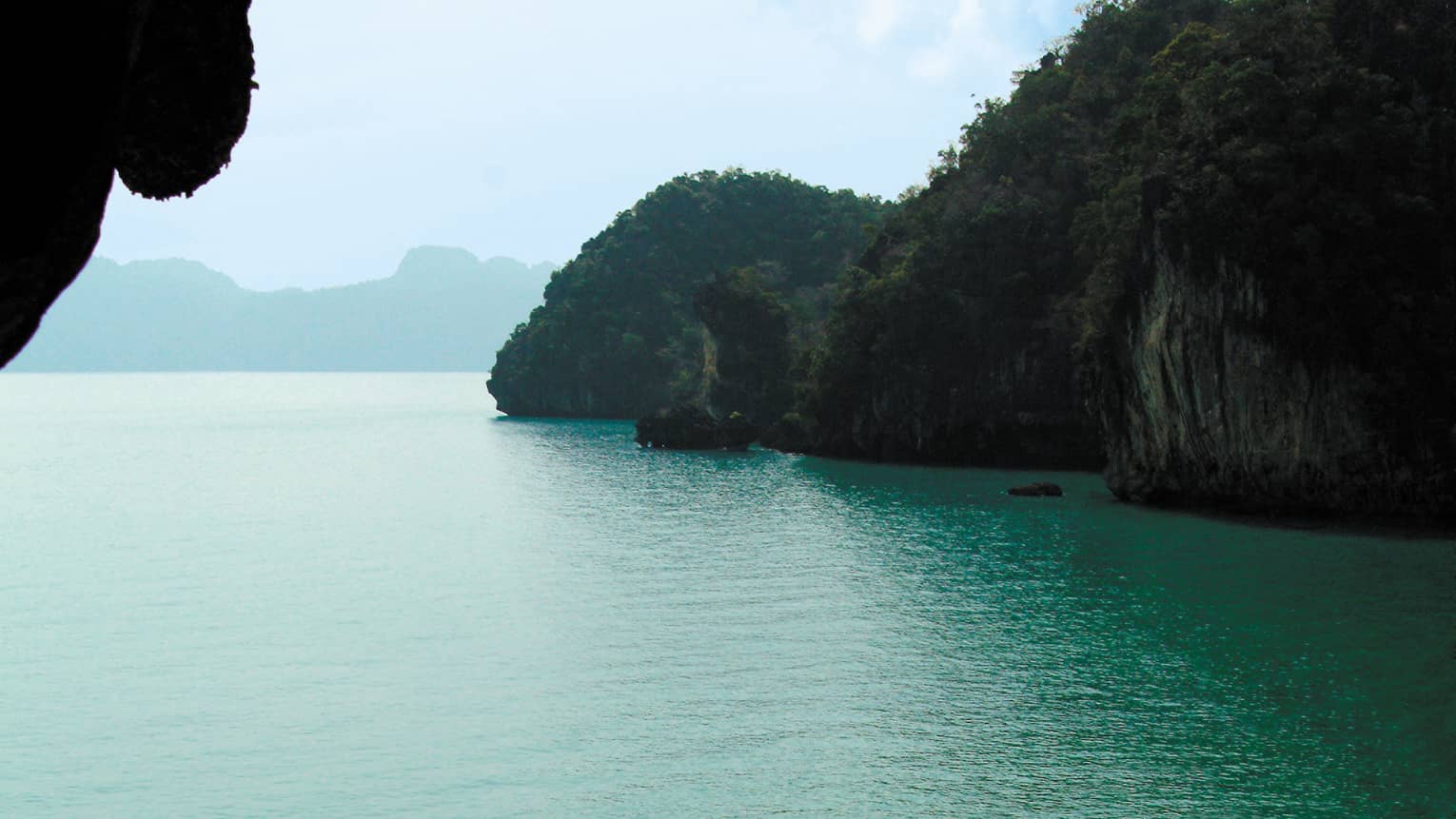 View from a cave out to the seat with a covered boat on the water