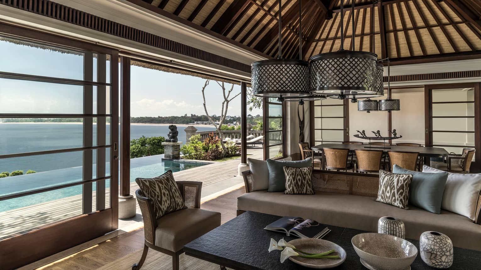 Royal Villa living room with beige sofas, round wicker chandeliers, sliding glass wall to sunny patio