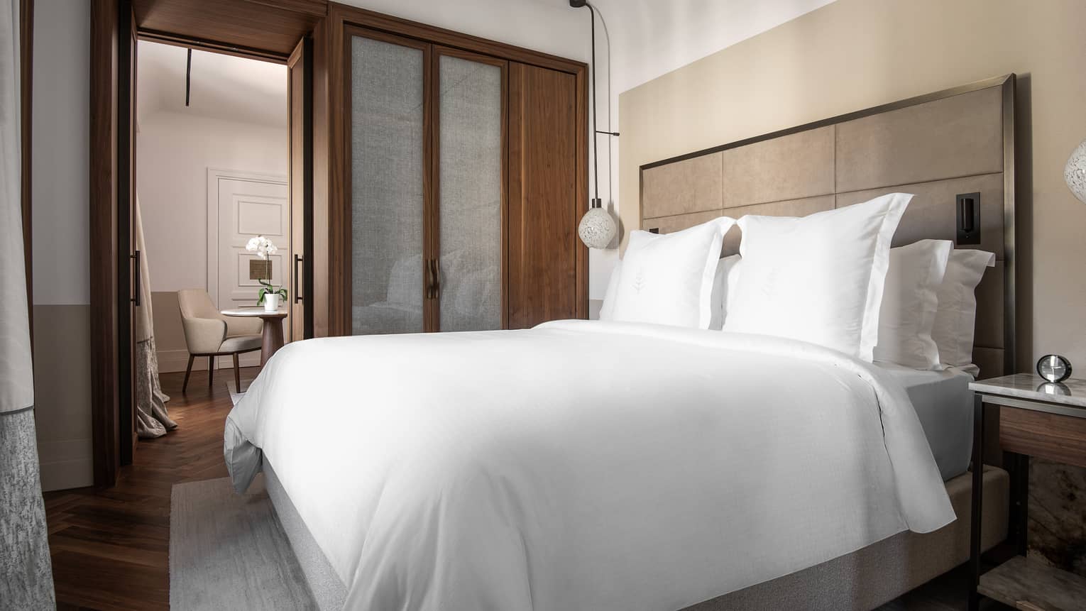 A bedroom with an open door to a chair and table.