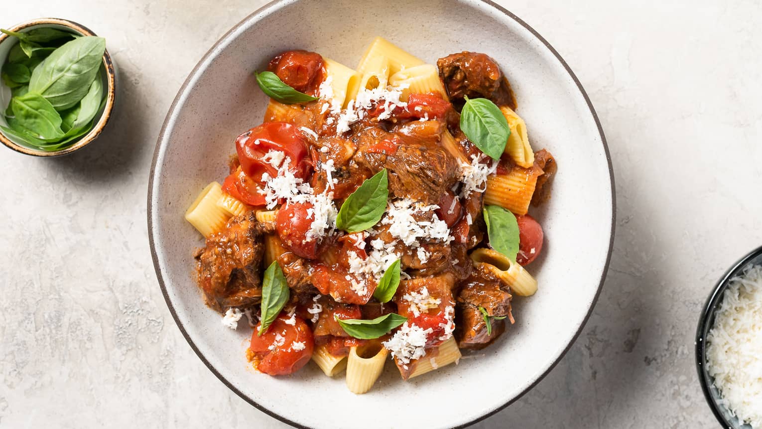 A bowl of pasta with tomatos and herbs.