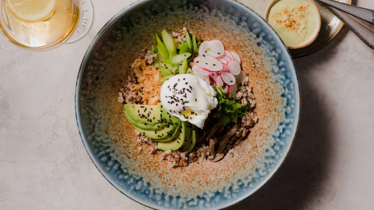 Korean grain bowl with avocado, radishes and fried egg in a patterned blue dish