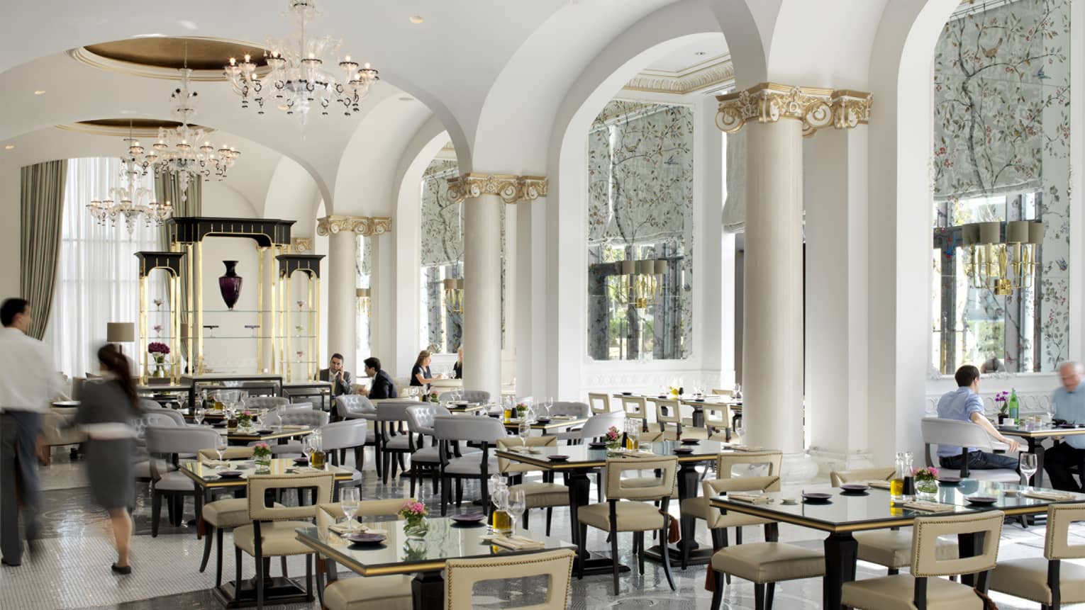 Bright dining room with tables under tall white and gold pillars