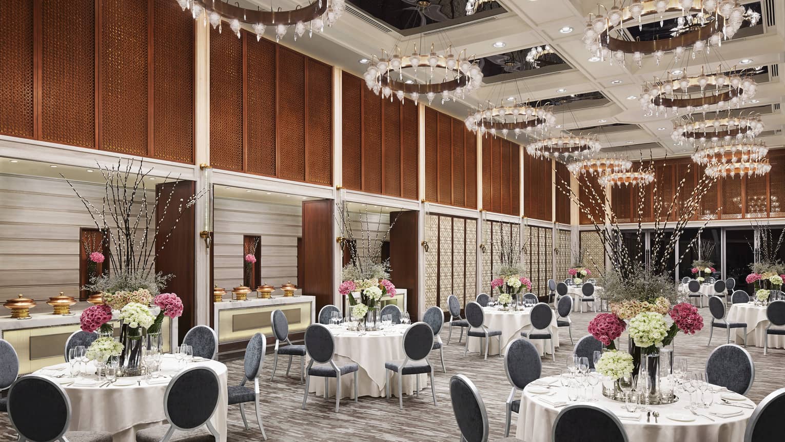 The Great Room ballroom with small banquet tables under high ceiling with round crystal lanterns