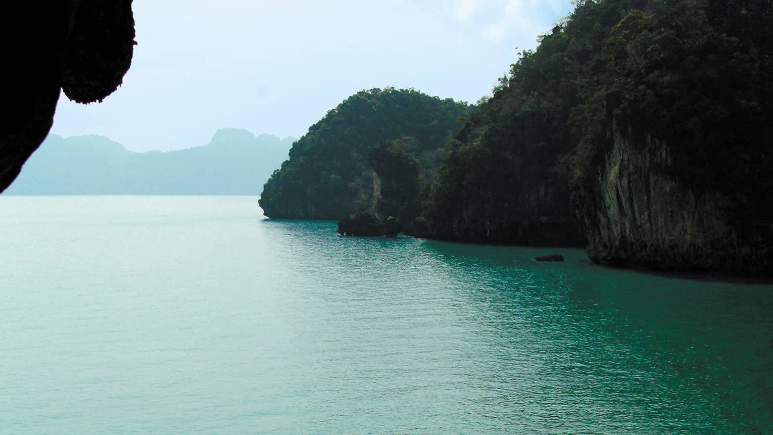View from a cave out to the seat with a covered boat on the water
