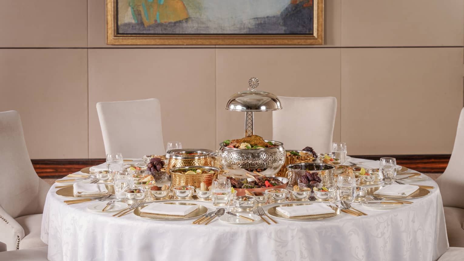A round table covered in white linens is set for a Ramadan feast for six