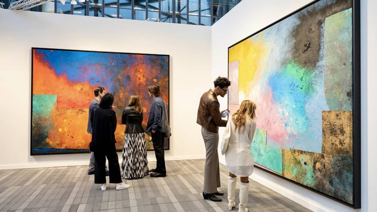People observing large paintings at an art gallery