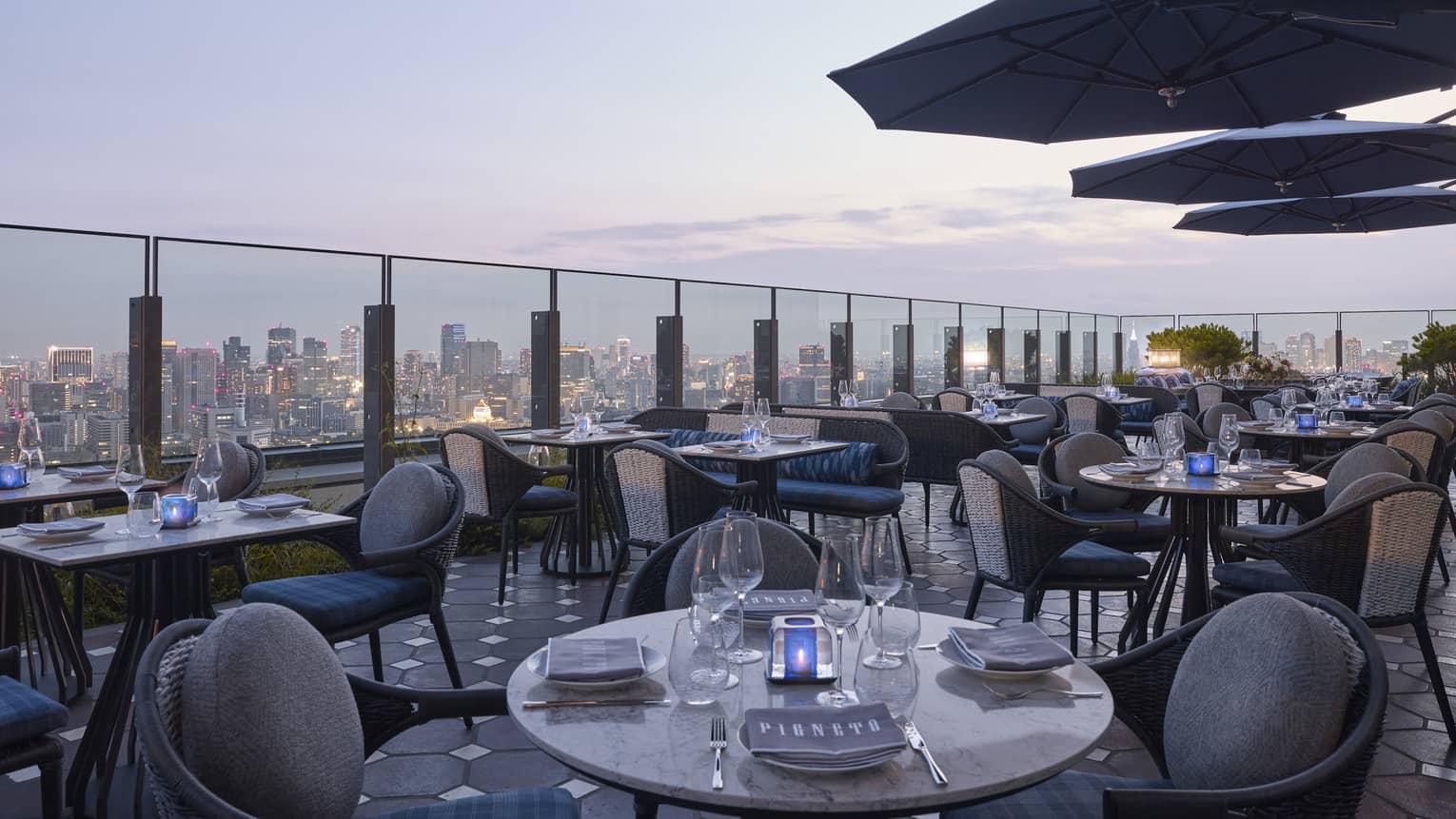 Pigneto Terraza rooftop patio dining tables at dusk, city view below